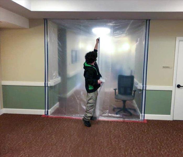 Employee putting up mold containment equipment for job