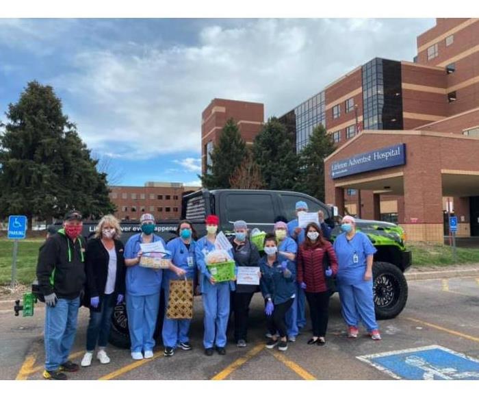 Group of people some nurses standing in front of a hospital accepting baskets of goodies as a thank you