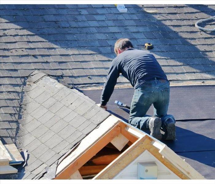 Man tarping a roof, Roof damaged, missing shingles on a roof