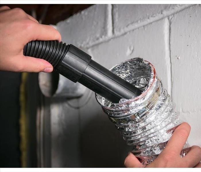 Vacuum cleaning a flexible aluminum dryer vent hose, to remove lint and prevent fire hazard.