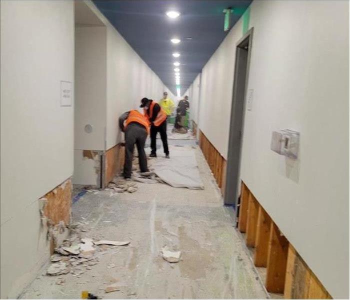 Servpro workers performing flood cuts on drywall