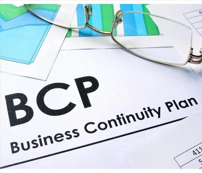 Theres a paper that says Business Continuity Plan on top there is a pen and a pair of eye glasses